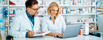 Boccette di integratori, capsule o tisane su un tavolo di legno chiaro, con un tocco verde naturale.